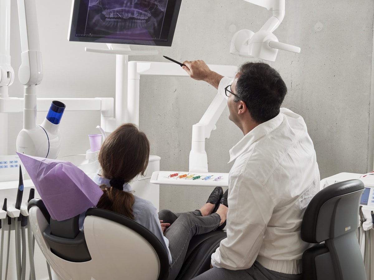 Ortodontista analisando radiografia com paciente em consultório